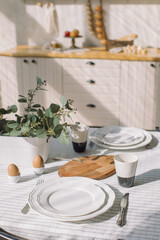 Table served with plates, coffee cups and food for breakfast at modern kitchen. Family time concept, copy space.