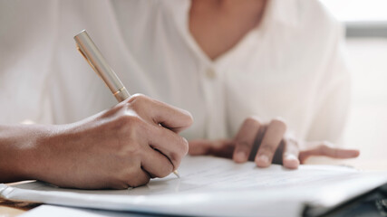 closeup cropped hands of young female writing day plan in notebook at the workplace.