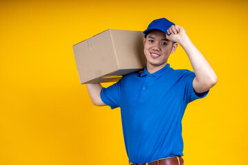 Fototapeta na wymiar Asian delivery man holding parcel box over yellow isolate background. Work from home and delivery concept.