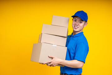 Asian delivery man holding parcel box over yellow isolate background. Work from home and delivery...