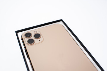 Gold-colored smartphone with three cameras on a white background