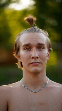 Portrait shirtless blond young man with chain in park