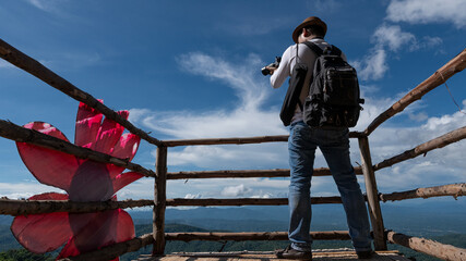 A man standing, taking a picture of the scenery at Moncham, Chiang Mai, Thailand