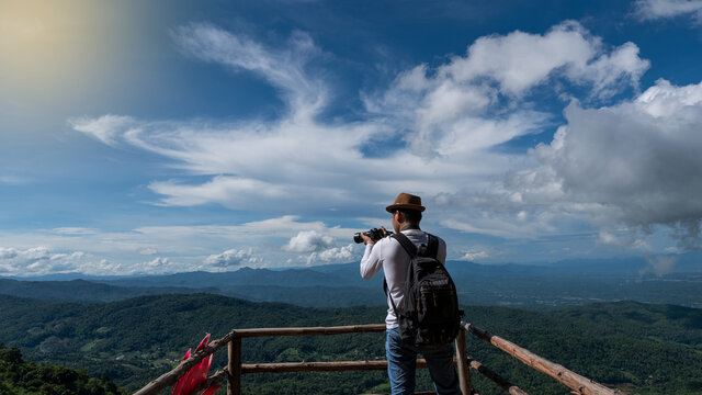 Rear view, a man standing to take pictures of the scenery at Moncham, Chiang Mai, Thailand
