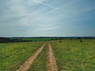 road among the green field against the blue sky