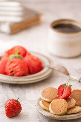 Trendy home breakfast with tiny pancakes and strawberry on white table. 