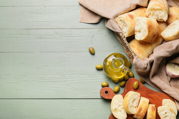 Bottle of tasty olive oil and bread on wooden background