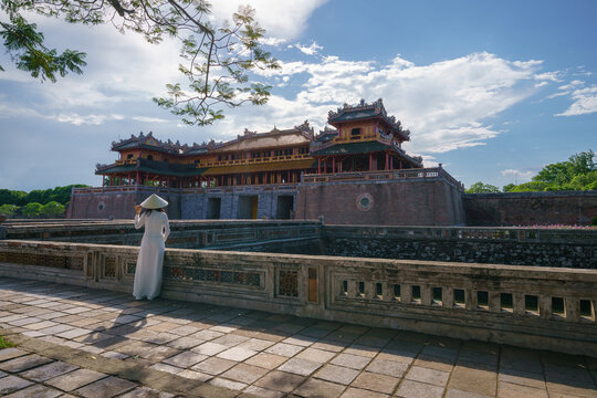 Ngo Mon gate - the main entrance of forbidden Hue Imperial City in Hue city, Vietnam, with Vietnamese girl wearing traditional dress Ao Dai