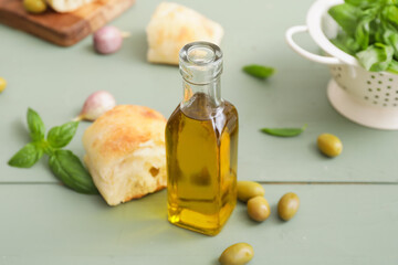 Bottle of tasty olive oil and bread on table