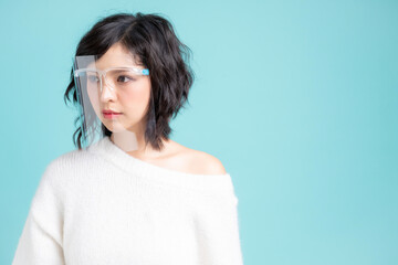 Obraz premium Young Asian woman wearing a face shield. Isolated image over light blue background.