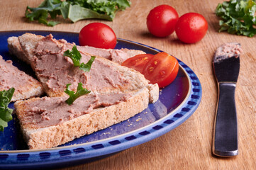 Brussels pate on toast with tomatoes and green salad next to pate knife.