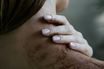 DIY Coffee scrub. Beauty skin care. Young woman putting coffee scrub on her neck and shoulders.
