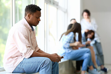 Lonely African-American man near window in hall. Stop racism