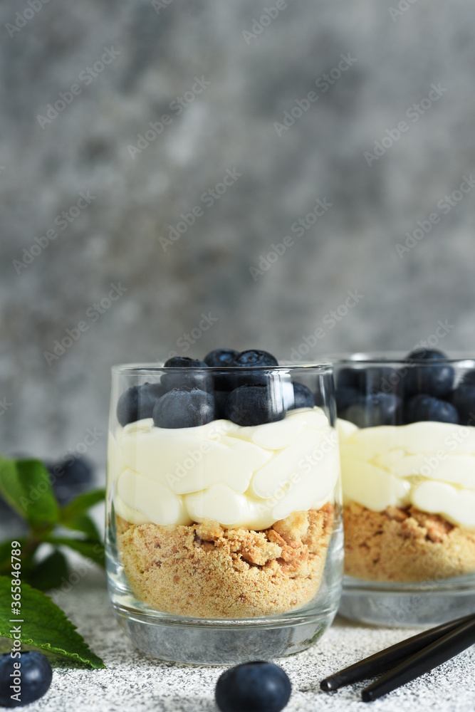 Canvas Prints Cheesecake with cookies and berries in a glass on a light concrete background.