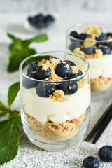Cheesecake with cookies and berries in a glass on a light concrete background.