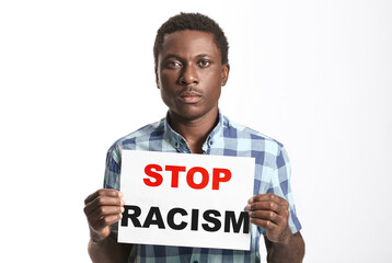 Sad African-American man with poster on white background. Stop racism