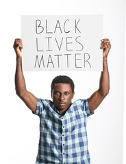 Sad African-American man with poster on white background. Stop racism