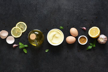 Homemade mayonnaise on a black background. Ingredients for making the sauce: egg, butter, mustard.