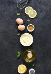 Homemade mayonnaise on a black background. Ingredients for making the sauce: egg, butter, mustard.
