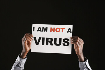 African-American man with poster on dark background. Stop racism