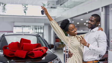 portrait of beautiful african married couple came in dealership to buy their first family car. happy customers make purchase, choose