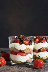 Dessert with cream cheese, strawberries and chocolate in a glass on a concrete background. Tiramisu with strawberries.
