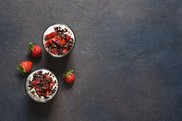 Dessert with cream cheese, strawberries and chocolate in a glass on a concrete background. Tiramisu with strawberries.