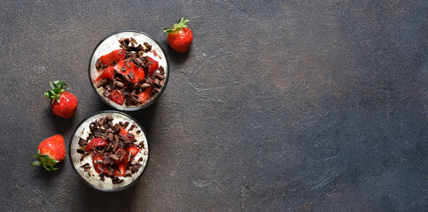 Dessert with cream cheese, strawberries and chocolate in a glass on a concrete background. Tiramisu with strawberries.