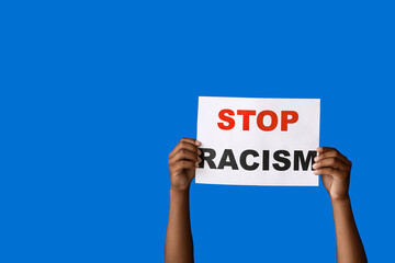 African-American teenage boy with poster on color background. Stop racism