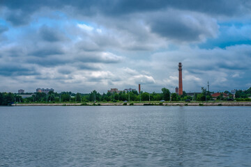 Landscape with a lake against the background of a small town and a sky with clouds (Russia, Moscow region, Lake Senezh).