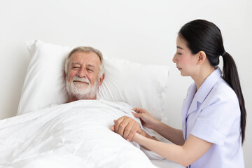 Obraz premium Nurse cares for elderly man lying in bed