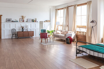 Vintage studio apartment interior in light colors in old style. huge room with large windows with a living room area and a bedroom area. direct sunlight inside.