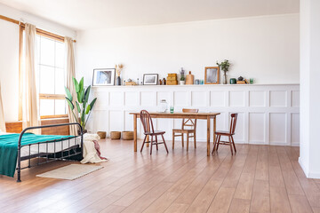 Vintage studio apartment interior in light colors in old style. huge room with large windows with a living room area and a bedroom area. direct sunlight inside.