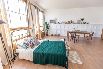 Vintage studio apartment interior in light colors in old style. huge room with large windows with a living room area and a bedroom area. direct sunlight inside.