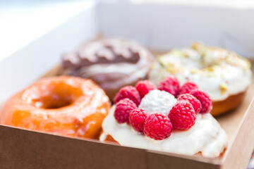 four pieces of totally different colorful and delicious looking donuts in ecological carton box. appetising fast food dessert