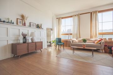 Vintage studio apartment interior in light colors in old style. huge room with large windows with a living room area and a bedroom area. direct sunlight inside.