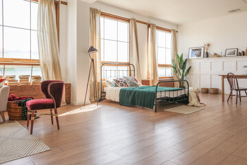 Vintage studio apartment interior in light colors in old style. huge room with large windows with a living room area and a bedroom area. direct sunlight inside.