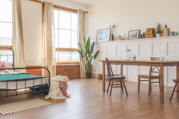 Vintage studio apartment interior in light colors in old style. huge room with large windows with a living room area and a bedroom area. direct sunlight inside.