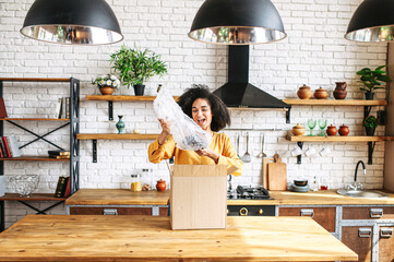 Unpacking the long-awaited package. A young African-American girl excitedly takes out an internet...