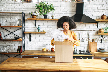 The online order does not meet expectations. An African-American girl unpacks an order box with a...