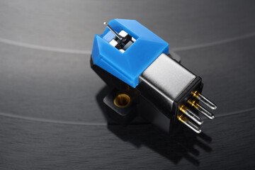 A magnetic phonograph cartridge on vinyl record groove.