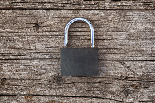 the old padlock lies on the wooden surface