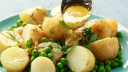 Warm vegetarian new baby potato salad with petit pois peas, Dijon mustard and capers dressing, served with fresh dill