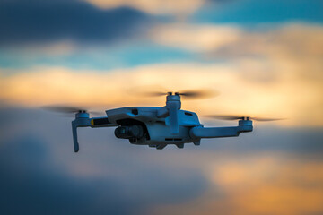 Small camera drone flying at cloudy sunset