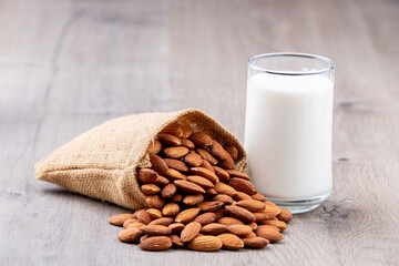 Close Up glass of Almond milk in a glass with Almond seeds. an wooden background
