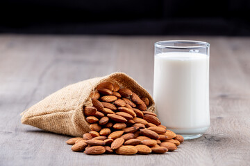 Close Up glass of Almond milk in a glass with Almond seeds. an wooden background