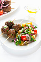 Lula kebab from lamb on a wooden skewer with a salad from Cherry tomatoes, red onions and green beans. White background. Selective focus.