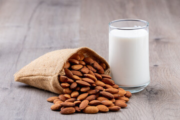 Close Up glass of Almond milk in a glass with Almond seeds. an wooden background