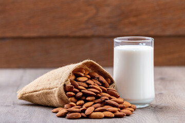 Close Up glass of Almond milk in a glass with Almond seeds. an wooden background
