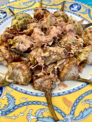 Fried artichokes on a ceramic plate with an ornament. National Mediterranean cuisine